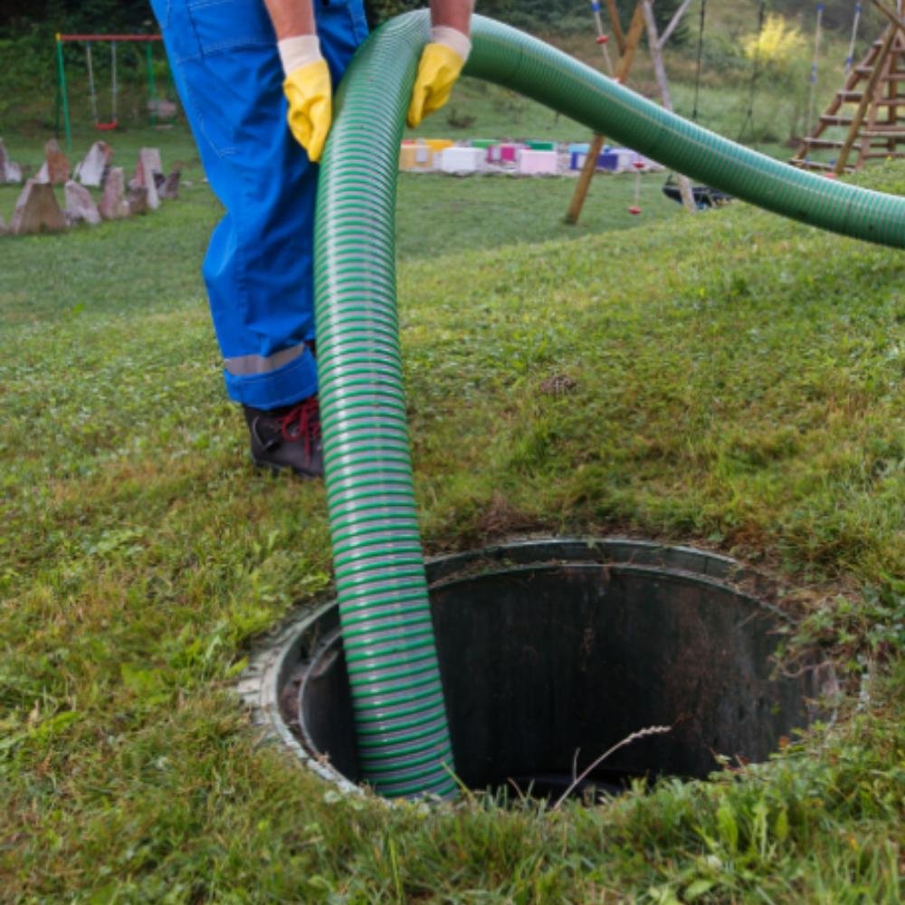 Worker placing septic service hose into septic tank opening